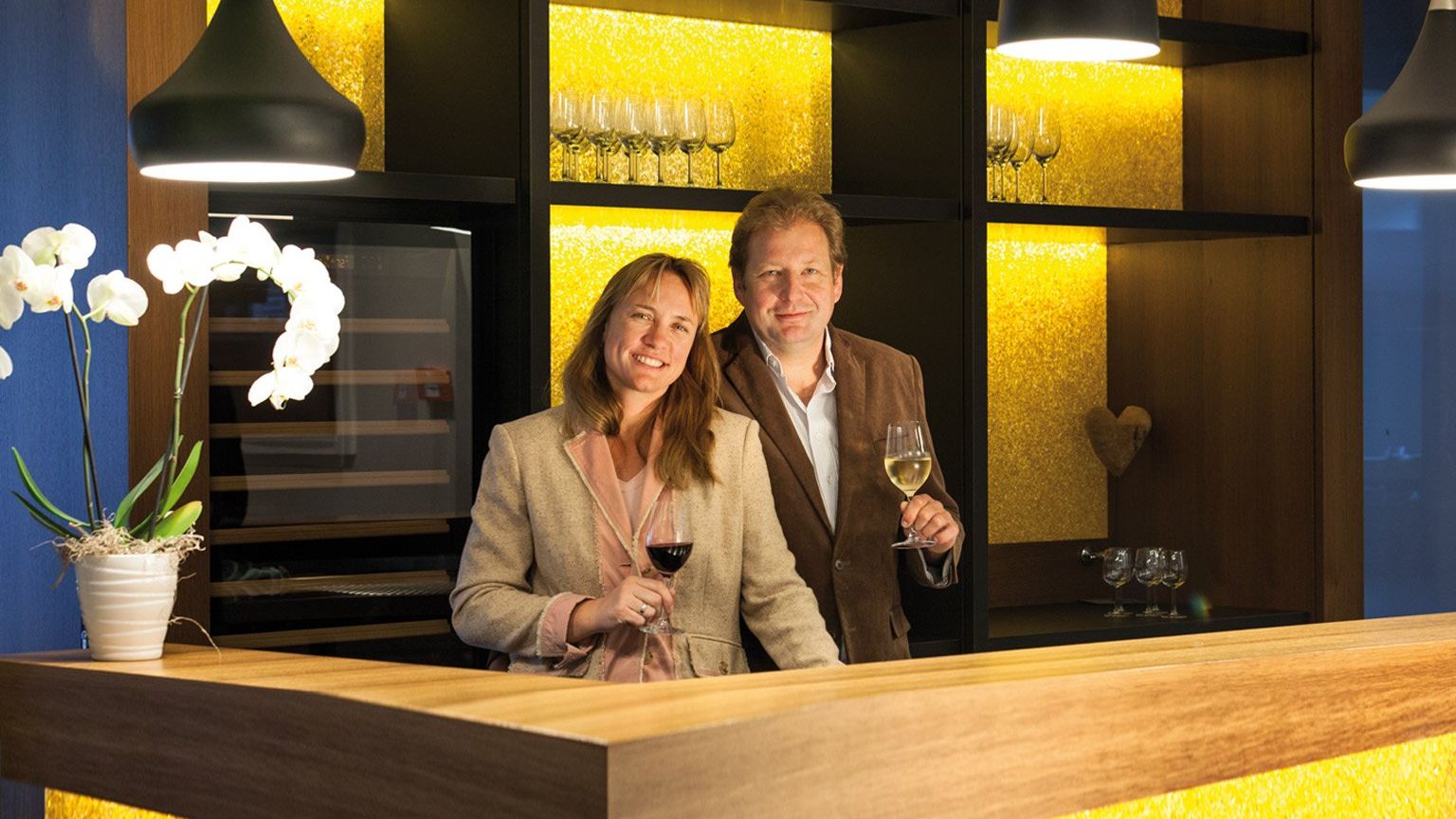 Hinter dem Tresen der Hotelbar steht das Inhaber Ehepaar Petra Brand und Andreas Biegler